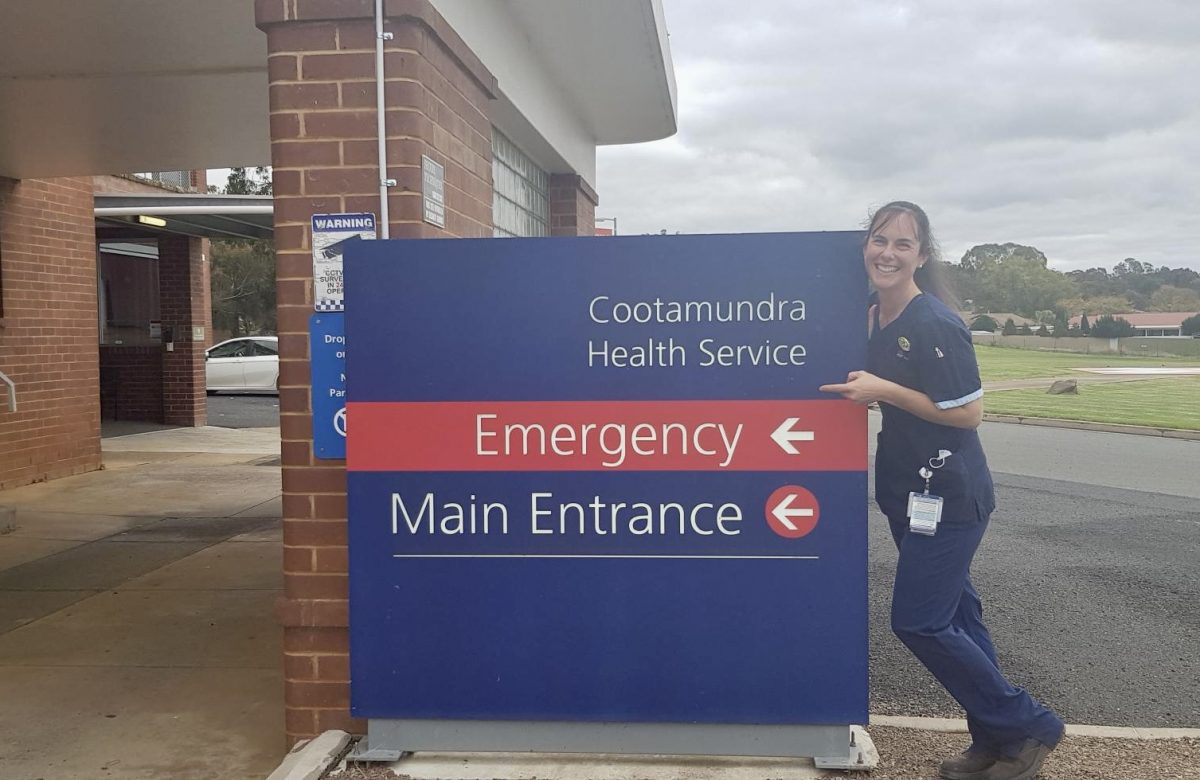 Nurse smiling next to Hospital Emergency sign