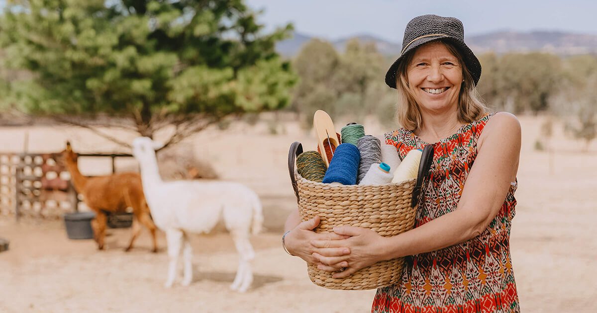 woman holding baskets of fibres and alpacas