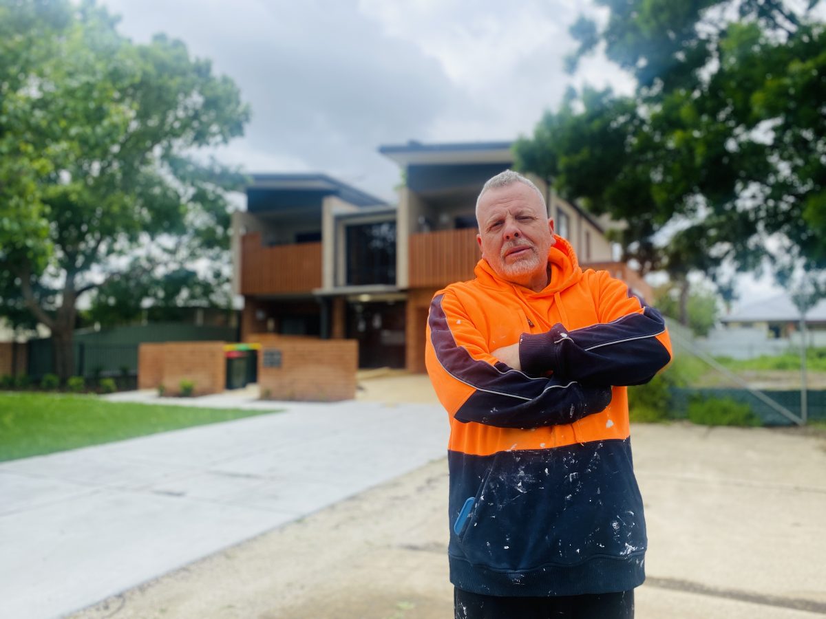 Richard Foley with arms crossed outside public housing dwelling.