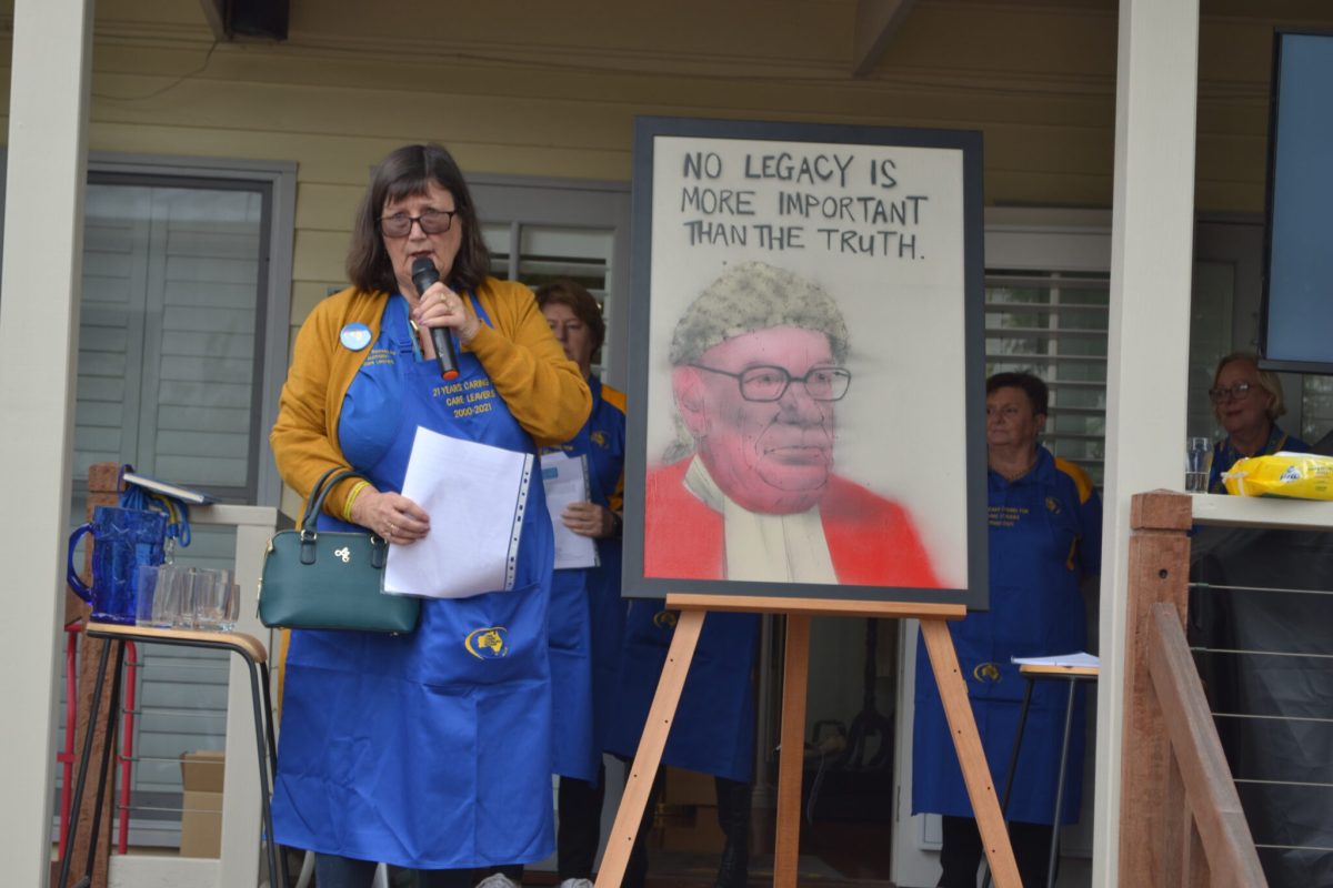 Leonie Sheedy with a microphone next to a painting 