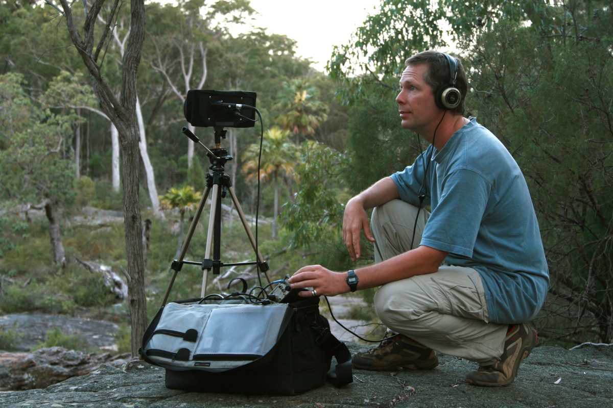 man in forest recording nature sounds