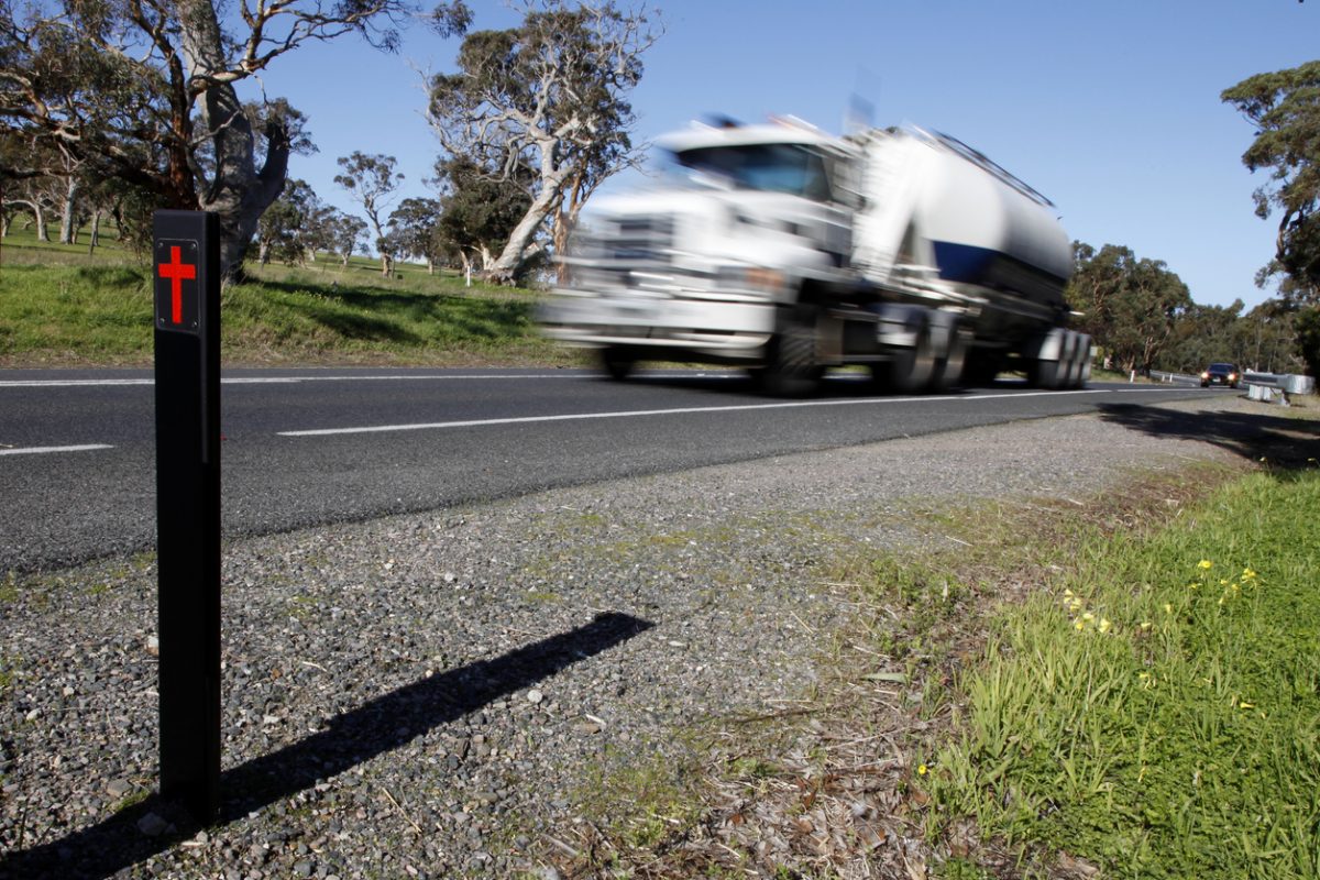 A truck speeds past a fatility marker on a highway.